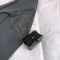 Borsa a busta in gelatina nera lucida con catena dorata su sfondo blazer minimalista - Nero