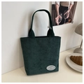 Detalle del bolso tote de pana verde oscuro con textura vertical y parche del logo FANYISSA - Verde