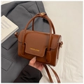 Detail der braunen Kunstleder-Handtasche mit goldener Aufschrift und dünnem Schultergurt - Braun