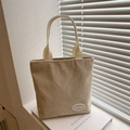 Bolso tote de pana beige con asas tejidas sobre un alféizar con luz suave natural - Caqui