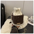 Detailed view of pearl handle and brown snakeskin bucket bag on a minimalist background - Coffee