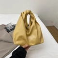 Ginger yellow soft leather cloud bag with unique knotted handle on white bedding - Yellow