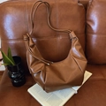 Minimalist large brown leather hobo shoulder bag with drawstring knot detail on sofa - Brown