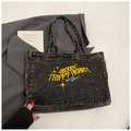 Gros plan sur le sac en jean délavé avec broderie jaune vintage et motifs d'étoiles - Noir