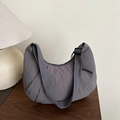 Grey crescent nylon shoulder bag with wide strap and pleated detail on wooden table - Gray