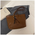 Detailed macro view of brown lychee grain leather tote bag with gold key and fringe charm - Brown