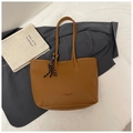 Detail of a brown textured leather tote bag with braided charm and wide base for capacity - No Pendant / Brown