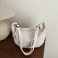 Sac hobo beige texturé avec bandoulière et charm mignon posé sur une table en bois - Blanc