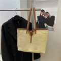 Beige geflochtene Stroh-Tote-Bag mit braunen Ledergriffen am Metallständer hängend - Braun