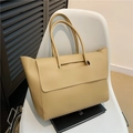 Minimalistische beige PU-Leder-Einkaufstasche mit Klappverschluss auf weißem Stuhl - Khaki
