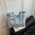 Light blue faux leather tote bag with pearl and lace bow charm on a white book - Blue