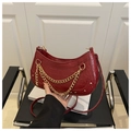 Gros plan d'un sac à main bordeaux motif crocodile avec chaînes dorées et clous en métal - Rouge