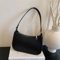 Minimalist black baguette bag with lychee texture and silver zipper on white books - Black