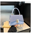 Nahaufnahme der hellblauen Handtasche mit gestreifter Stoffstruktur und goldenem Drehverschluss - Blau