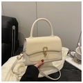 Detail of cream square handbag showing woven texture flap and golden horseshoe buckle - White