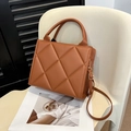 Elegante braune Stepptasche mit goldenen Beschlägen und verstellbarem Riemen auf Stuhl - Braun