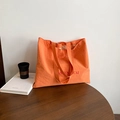 Minimalist orange nylon tote bag with red letter print on a rustic wooden table - Orange