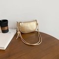 Golden crescent shoulder bag with lychee texture and knot detail strap on wooden table - Gold