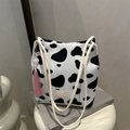 Schicke Bucket Tote Bag mit Kuhmuster, weißen Griffen und einem rosa Quastenanhänger - Kuhmuster