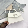 White faux leather crossbody bag with silver metal bow detail and top handle design - White