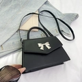 Elegant black lychee grain leather handbag featuring a large silver bow metal buckle - Black