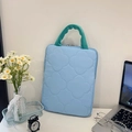 Hellblaue gesteppte Laptoptasche mit Kleeblattmuster und grünen Tragegriffen - Vertikales Blau