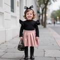 Detail of girls' black ribbed top with ruffle shoulders and pink pleated faux leather skirt - Black Top + Pink Skirt