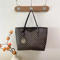 Brown monogram tote bag with gold M pendant hanging on a wall hook in cozy setting - Brown