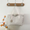 Off-white tote bag with grey M letter print and gold charm on a wall hook - White
