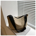 Detail of khaki nylon dumpling bag with black strap and zipper on a decorative book - Khaki