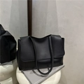 Bolso tote negro minimalista con textura de cuero, asas largas y cierre de solapa - Negro