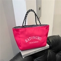 Pink nylon tote bag with white lettering and rope handles on a white book display - Rose Red