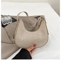 Detail of golden woven crescent handbag showing textured material and metallic zipper - Gold