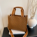 Borsa tote monogram vintage marrone con manici in tela e tracolla sopra un libro - Marrone