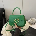 Borsa a sella verde in pelle e glitter con fibbia a D dorata tenuta in mano - Verde