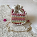 Bunte gewebte Mini-Beuteltasche mit Perlengriff und goldener Kette in 45-Grad-Ansicht - Rosenrot