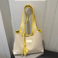 Borsa tote in tela a righe gialle e bianche con coulisse e manico sopra dei libri - Giallo