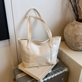 Schicke beige Tragetasche mit Blumenstickerei und Nieten auf einem Reisekoffer - Weiß