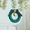 Mini green Christmas wreath with velvet bow and gold bell hanging on snowy pine branch - Style A Green