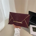 Elegante weinrote Umschlag-Clutch mit Schlangenmuster und Goldrand von Model gehalten - Rot