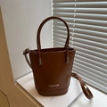 Brown leather bucket bag with top handles and adjustable shoulder strap in minimalist style - Tan