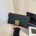 Minimalist black Saffiano leather clutch bag featuring a prominent gold geometric buckle - Black