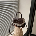 Mini brown bow shoulder bag with white lace trim and top handle in a lifestyle setting - Brown