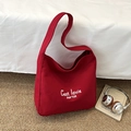 Chic red canvas tote bag with white minimalist lettering in a stylish lifestyle setting - Red