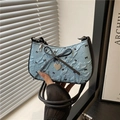 Borsa baguette azzurra strutturata con fiocchi neri e ciondolo a cuore mostrata a mano - Blu