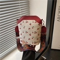 Mini cherry print bucket bag with contrast red trim and wide geometric woven strap - Red