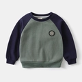 Detail van wafelgebreide stof en raglanmouwen op dit kindersweatshirt met ronde hals - 90cm / Groen Patchwork