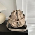 Sac seau beige minimaliste avec bandoulière réglable posé sur un bureau noir - Kaki