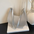 Borsa a spalla a mezzaluna argento minimalista con trama a grana su sfondo di un libro - Argento