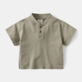 Detailed view of kids greyish green henley shirt collar with two dark buttons and logo label - 90cm / Tan